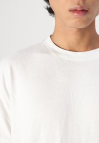 White cotton t-shirt with a round neckline and short sleeves, featuring a smooth texture and minimalistic design.