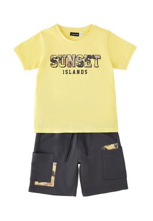 Żółta koszulka z krótkim rękawem z napisem „SUNSET ISLANDS” oraz ciemnoszare spodenki z bocznymi kieszeniami i żółtymi wzorzystymi akcentami.