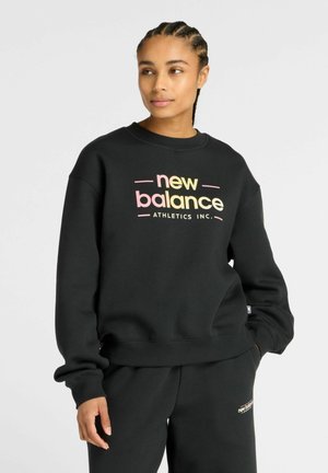 Sweatshirt noir en matériau doux avec un logo "new balance" dégradé en rose et jaune. Poignets et ourlet côtelés.