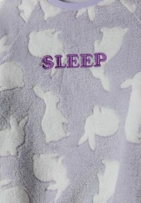 Lila fleece-topp med vita kaninsilhuetter och ordet "SÖMN" broderat i lila. Mjuk struktur och rund halsringning.