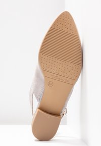 Semelle d'une chaussure beige à bout pointu avec grip texturé, talon bloc, taille 37, et nom de marque "Tamaris" visible sur la semelle.
