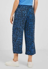 Culottes à motifs floraux bleus avec une taille élastique, design à jambes droites et longueur courte, associées à des baskets blanches.