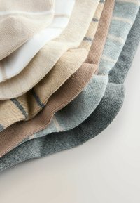 Piecas sarullētas zeķes dažādās krāsās: bēša, balta, brūna, gaiši zilā un tumši pelēkā. Teksturēts adījuma dizains ar smalkām svītrām dažās no tām.