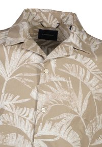 Chemise beige à manches courtes avec un motif de feuilles de palmier blanches, dotée d'un col pointu et d'une fermeture à boutons. Fabriquée en tissu léger.