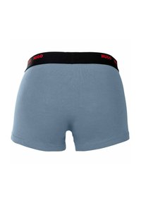 Blue cotton boxer shorts featuring a black waistband with red "HUGO" logo. Smooth texture and fitted design with short legs.