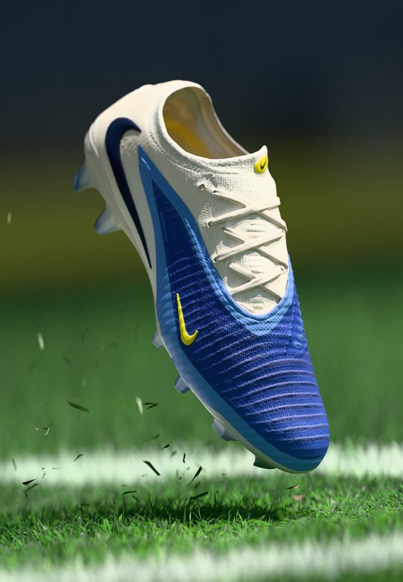 Nike football boot with a cream upper, blue accents, textured finish, and yellow logo, designed for optimal grip on grass surfaces.