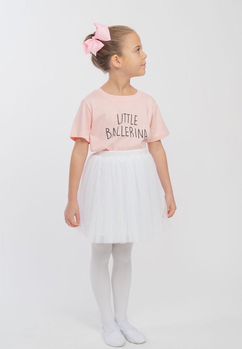 Rosa Baumwoll-T-Shirt mit dem Text "KLEINE BALLERINA", weißer Tüllrock, weiße Strumpfhosen und Ballettschuhe. Die Haare sind mit einer rosa Schleife gestylt.