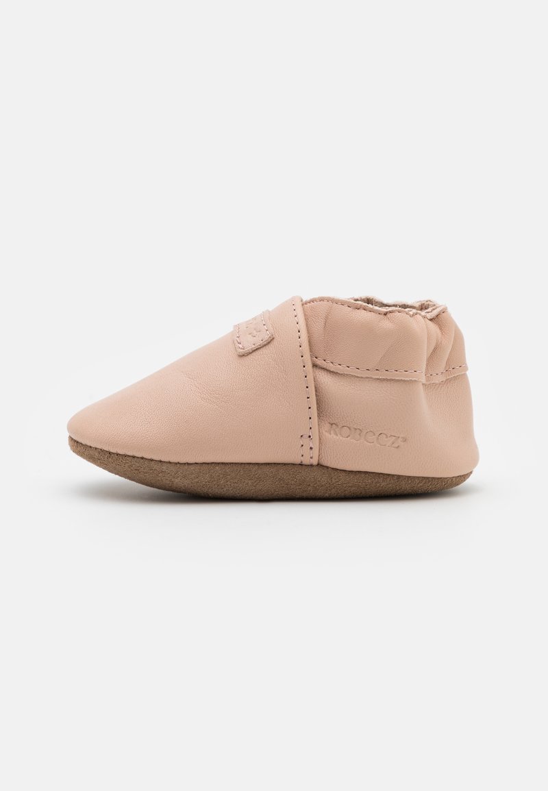 Δερμάτινο μωρουδιαίο παπούτσι σε απαλό ροζ με στρογγυλή μύτη και ελαστική επάνω επιφάνεια. Σχεδιασμένο για άνεση, με μπεζ σουέτ σόλα και ραμμένες λεπτομέρειες.