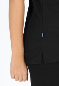 Camicia in tessuto nera con fessure laterali, dotata di un piccolo accento con bandiera blu e gialla che contrassegna la cucitura in basso.