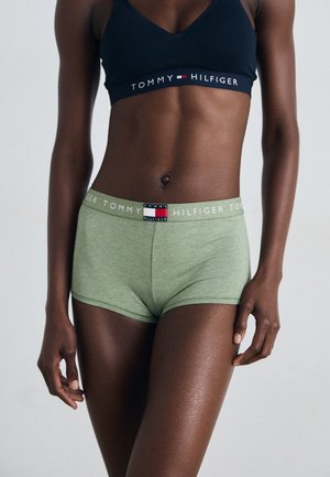 Grønne bomullsblandingsshorts har en logo-linning med røde og blå detaljer. En mørk sports-bh har en matchende logo-bånd.