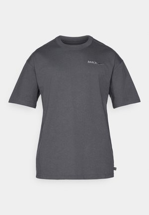 T-shirt a maniche corte color grigio scuro con collo tondo, con piccolo testo "BARÇA" e logo swoosh di Nike sul lato sinistro del petto.