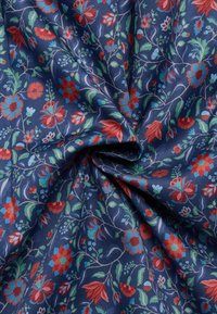 Marineblauwe stof met een bloemenpatroon dat rode, blauwe en groene bloemen en bladeren bevat, met een gestructureerd oppervlak en complexe ontwerpen.