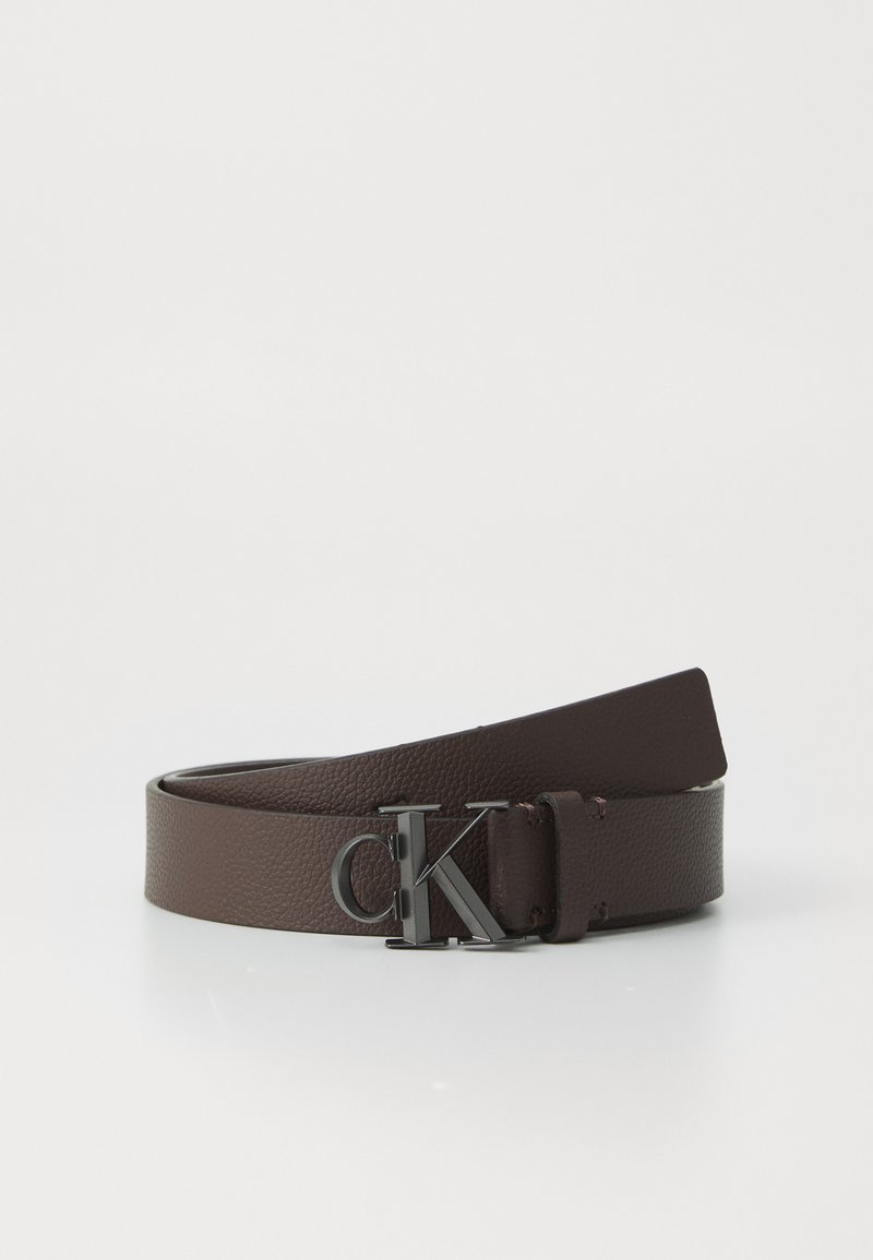 Dark brown leather belt rolled with black metallic "cK" buckle on white background.