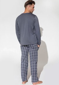 Szara koszulka z długim rękawem w połączeniu z granatowym piżamowym spodniami w kratę z białym wzorem, wykonana z miękkiego, komfortowego materiału.