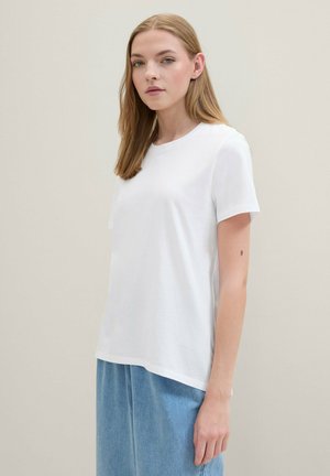 Witte katoenen t-shirt met korte mouwen, ronde halslijn, ontspannen pasvorm, gecombineerd met blauwe denim broek, eenvoudig en minimalistisch ontwerp.