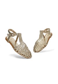 Sandalias de hilo dorado con punta abierta, correa ajustable en el tobillo y suela plana. Presentan un patrón texturizado y un diseño troquelado para mayor transpirabilidad.