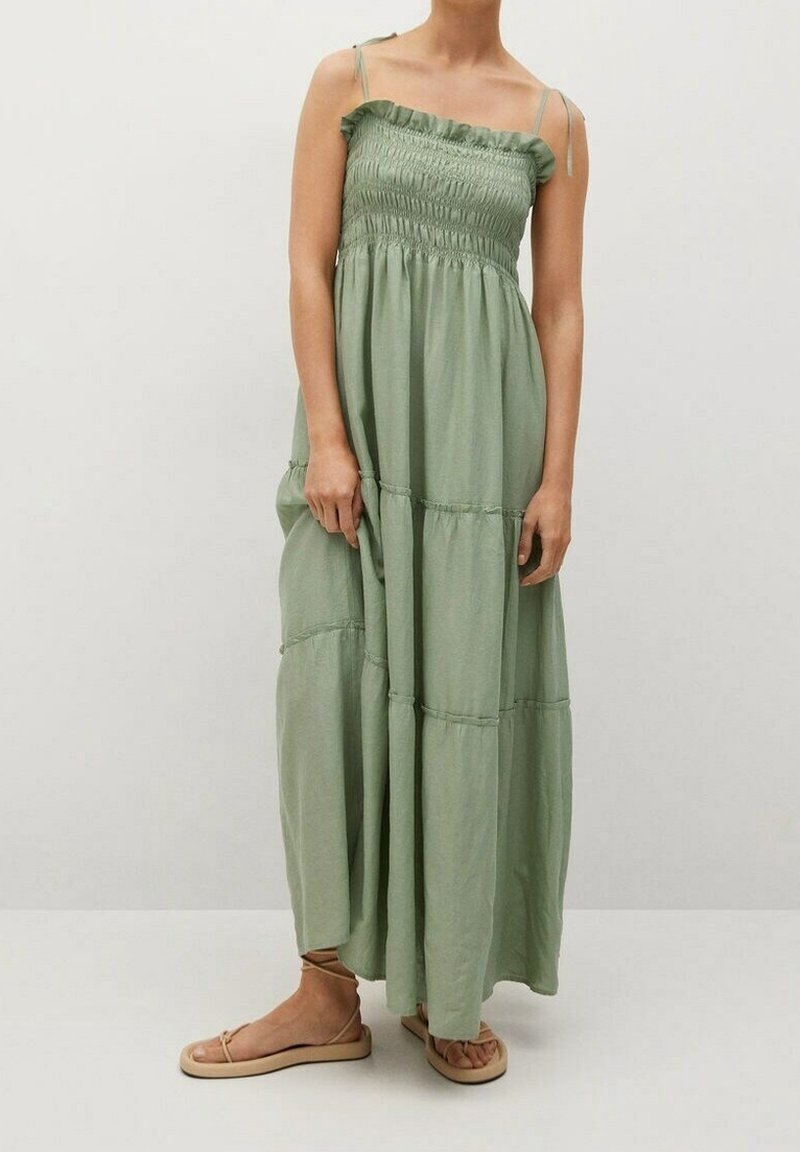 Robe longue en tissu vert doux, avec un corsage smocké, des bretelles fines réglables et un design à volants avec un léger froncement aux coutures.