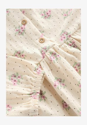 Abito di tessuto beige chiaro con piccoli pois marroni e motivi floreali rosa. Presenta chiusure con bottoni e maniche arricciate. Texture morbida.