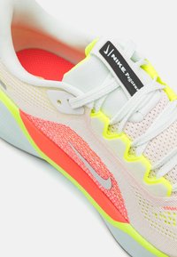 Zapatilla de running Nike Pegasus con una parte superior de malla en gris claro y acentos neón vibrantes, que cuenta con una entresuela de coral texturizada y un logo reflectante.