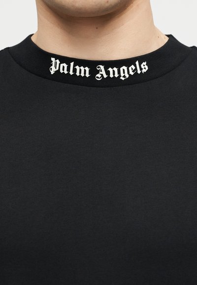 Primo piano di una maglietta nera con scollo rotondo con la scritta "Palm Angels" in carattere gotico bianco stampata lungo il collo.