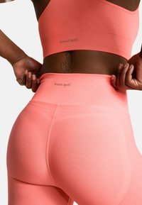 Koronkowy stanik sportowy i legginsy wykonane z elastycznego materiału, dopasowany krój, z subtelnym brandingiem "oceans apart" na pasku. Widoczne szczegóły teksturowe.