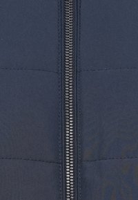 Μπλε ναυτικό πούφφερ μπουφάν μπροστά με οριζόντια ραφή, διαθέτοντας κεντρικό φερμουάρ και απλή, ματ υφή.