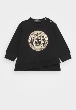 Sort langærmet toddler-skjorte med Medusa-hovedlogo i guld kontur, ribstrikkede ærmekanter, guld skulderknapper og flæsekantdetalje.