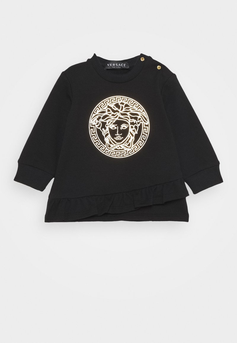 Chemise noire à manches longues pour tout-petit avec logo tête de Méduse en contour doré, poignets côtelés, pressions dorées aux épaules et détail volanté à l'ourlet.