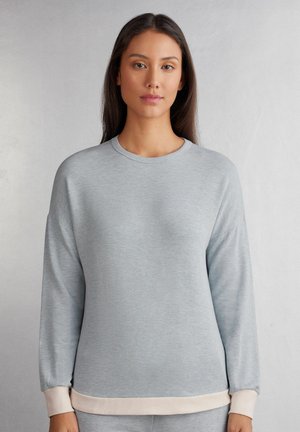 Ljusgrå sweatshirt med rund halsringning och långa ärmar. Muddarna och nederkant har en kontrasterande krämfärg. Mjukt, strukturerat tyg.