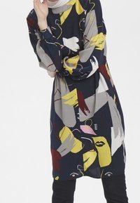 Merimiespuku, jossa on abstrakteja värikkäitä kuvioita keltaisessa, vaaleanpunaisessa, harmaassa ja punaisessa. Pitkät hihat, löysä istuvuus ja pyöreä kaula-aukko. Pehmeä kangas.