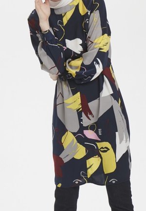 Robe marine avec des motifs abstraits colorés en jaune, rose, gris et rouge. Manches longues avec une coupe ample et un col rond. Tissu doux.