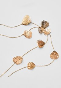 Collana in metallo dorato con pendenti a forma di fiori e foglie dalla texture particolare. Il design comprende forme e dimensioni variabili con una finitura lucida.