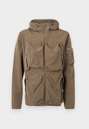 Καφέ σακάκι με κουκούλα, φερμουάρ στο μπροστινό μέρος και πολλαπλές μεγάλες τσέπες στο στήθος, στη μέση και στο αριστερό μανίκι.