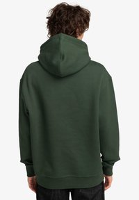 Grøn hættejakke lavet af blødt stof, med hætte, ribbede manchetter og kant, vist fra ryggen. Enkel design med minimale detaljer.
