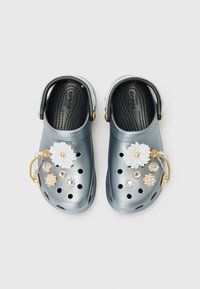 Crocs métalliques bleus avec des fleurs décoratives et des pierres précieuses. Comprend de nombreux trous de ventilation et une sangle arrière pour un ajustement sécurisé.