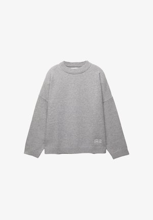 Szary, oversize sweter z prążkowanym okrągłym dekoltem i długimi rękawami. Posiada haftowany napis w lewym dolnym rogu. Miękka tekstura.