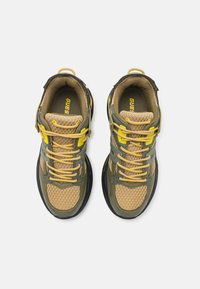 Sneakers in mesh e sintetici color verde oliva e giallo. Presentano lacci gialli, una tomaia in beige textured e una suola in gomma nera. Logo del marchio visibile.