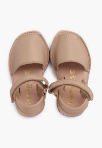 Sandali in pelle color beige chiaro, con forma arrotondata, fascia alla caviglia e dettagli cuciti. Logo dorato stampato sulla soletta.
