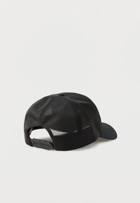 Črna mrežasta bejzbolska kapa z nastavljivim zapiranjem na zaponko, prikazana s hrbtne strani na beli podlagi.