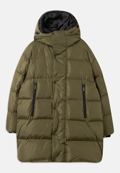 Veste rembourrée olive avec capuche, présentant un design matelassé, des poches zippées noires et des boutons pression sur le devant.