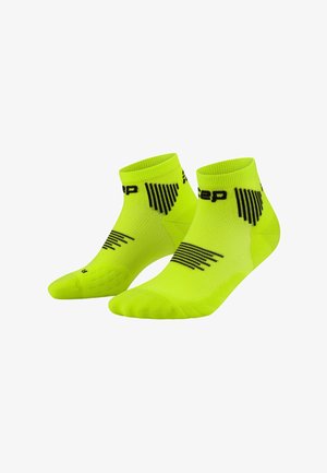Ein Paar neon-gelbe Knöchelsocken mit schwarzen geometrischen Mustern und Markentext auf weißem Hintergrund.