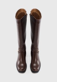 Καφέ δερμάτινες μπότες μέχρι το γόνατο με λεία υφή, κεκλιμένο μίσχο, πλαϊνά φερμουάρ και διακοσμητικό λουράκι στον αστράγαλο.