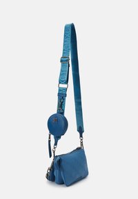 Blå crossbody taske med aftagelig rund møntpung og justerbar rem med præget tekst.