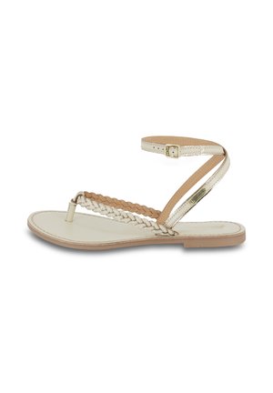 Sandali piatti con design intrecciato in pelle color crema e beige. Presentano una cinghia alla caviglia con fibbia e una suola piatta e liscia.