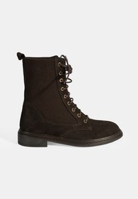 Bruine veterschoenen met een suède neus en een ribbelstof schacht met gouden oogjes. De zool is plat en zwart, wat een contrasterend detail biedt.