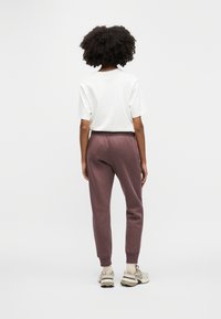 Λευκό κοντομάνικο μπλουζάκι συνδυασμένο με μπορντό φόρμες που έχουν ελαστικές μανσέτες και ζωνάκι με κορδόνι, ολοκληρωμένο με ανοιχτόχρωμα αθλητικά παπούτσια.