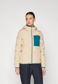 Beige dunjakke med en teal brystlomme, frontlukking med glidelås og hette. Har quiltet tekstur og kontrastfargede blå detaljer.