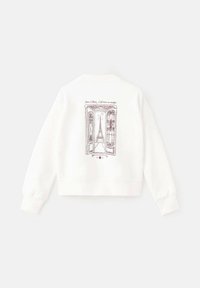 Sweatshirt blanc cropped avec un graphique violet représentant une porte ouverte, avec la Tour Eiffel visible à travers l'embrasure, et des accents décoratifs.