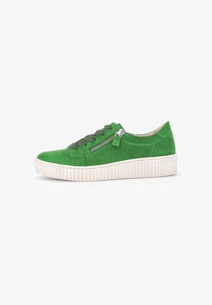 Groene suède sneaker met een witte textuurzool, voorzien van platte veters en een zijrits voor gemakkelijke toegang.