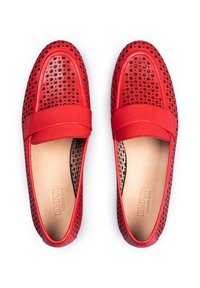 Mocassini in pelle rossa con design perforato, accenti neri e una texture liscia. Presentano una suola piatta e una larga fascia attraverso il collo del piede.